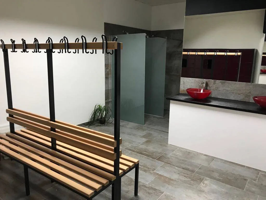 Vestiaires avec bancs en bois, casiers et douches individuelles